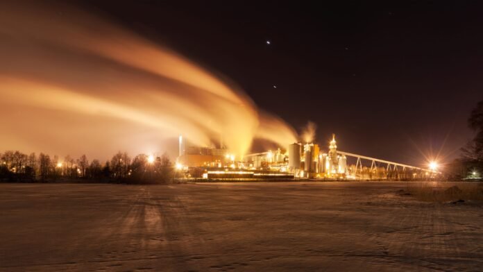 Factory emitting steam at night amid weaker global manufacturing demand in July 2026