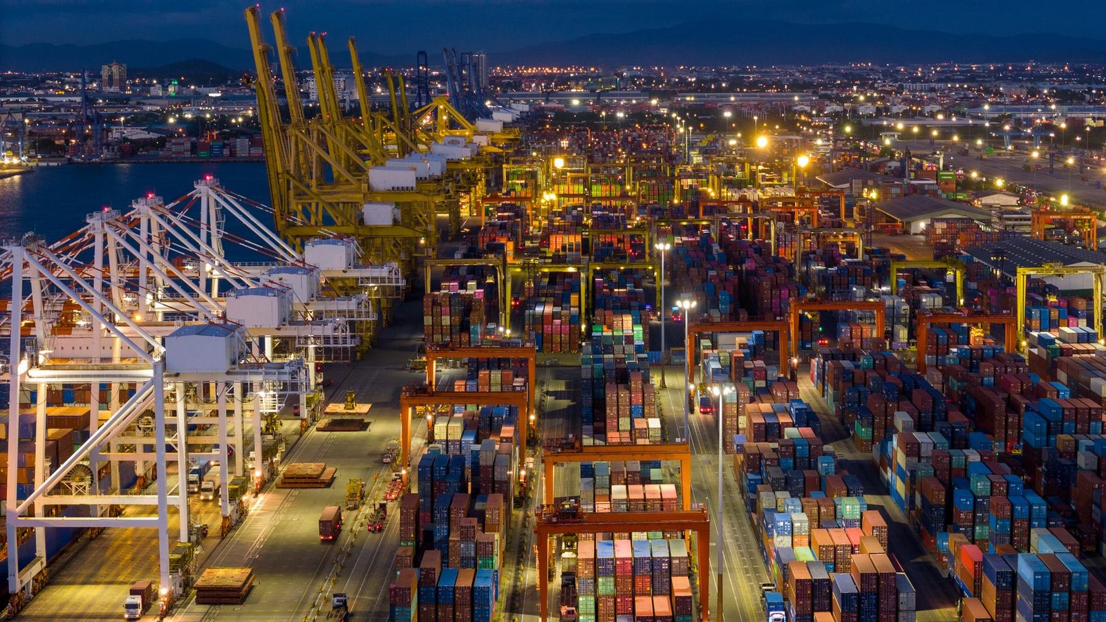 Shipping containers at a port at night as manufacturing demand weakens amid supply chain disruption